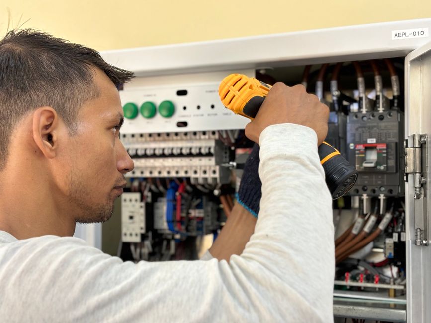 Electrician drilling into an indoor consumer unit during an installation